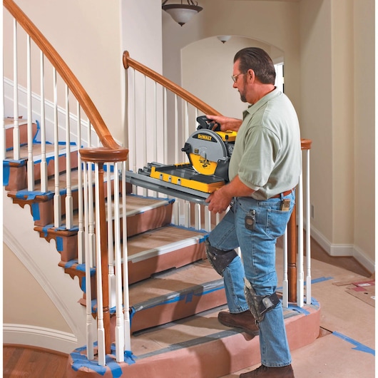 wet tile saw being carried by person on stairs