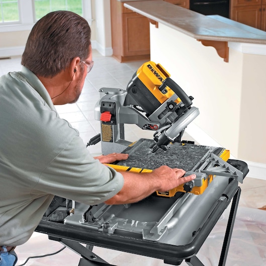 wet tile saw being used by person to cut tiles