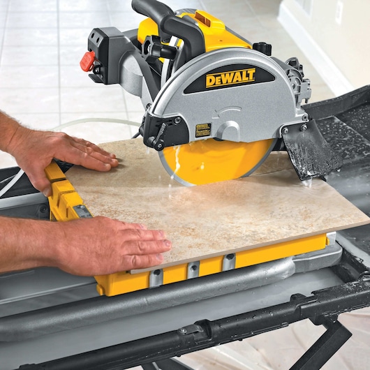 wet tile saw being used by person to cut tile in half