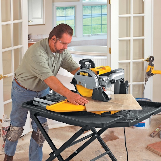 wet tile saw being used by person to cut tile diagonally