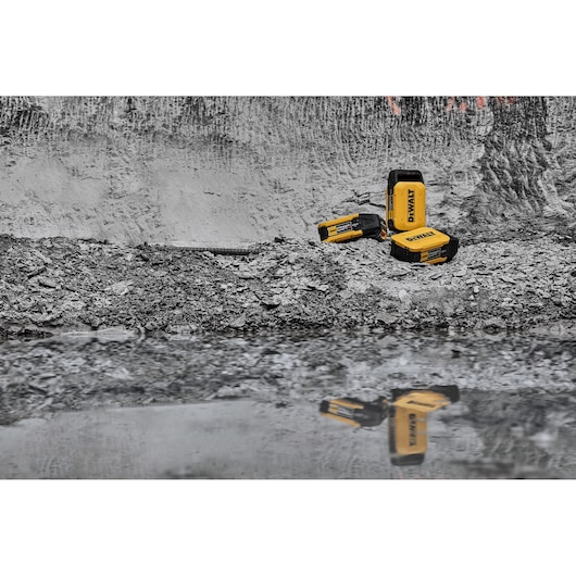 x3 Powershift 554WH batteries sit on concrete rubble and are reflected in water in the foreground