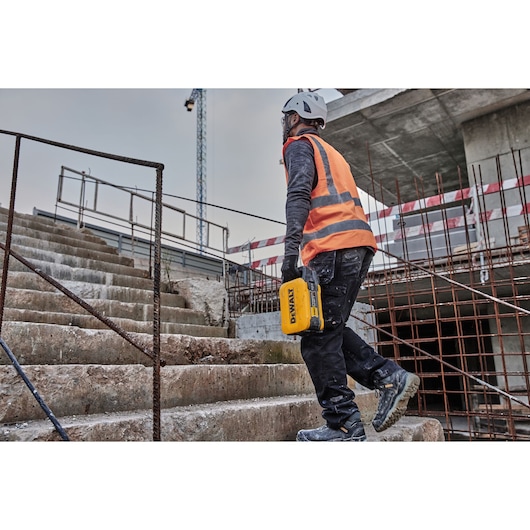 Powershift 554WH battery being carried by a construction worker walking up concrete steps