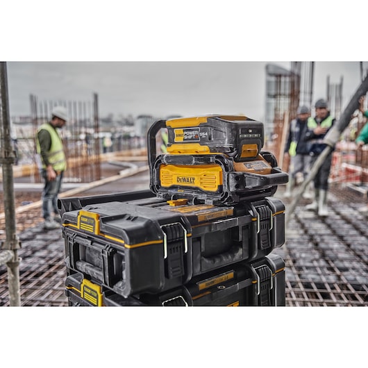 Powershift 554WH battery and Powershift charger DCBPSC0550 stacked on top of ToughSystem storage on a construction site