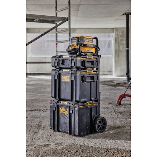 Powershift Charger DCBPSC0551 and Battery DCBPS0554 stacked on top of ToughSystem storage on a construction site