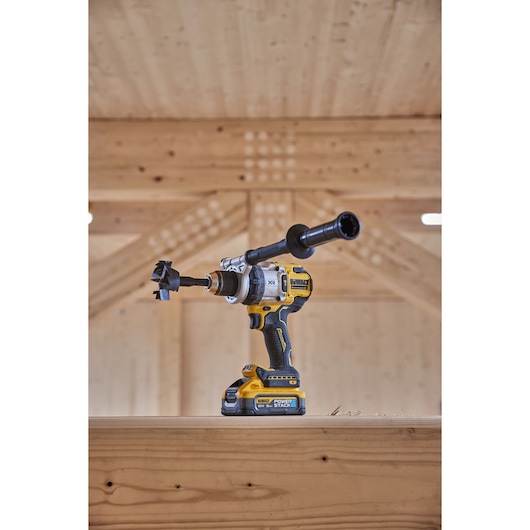 Angled view of 18V XR Brushless Premium Hammer Drill Driver with side handle and Powerstack 5Ah battery sitting on top of a wooden table