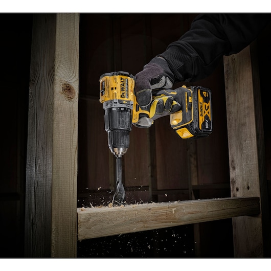 Worker in 100 years of DEWALT top drilling through timber stud wall
