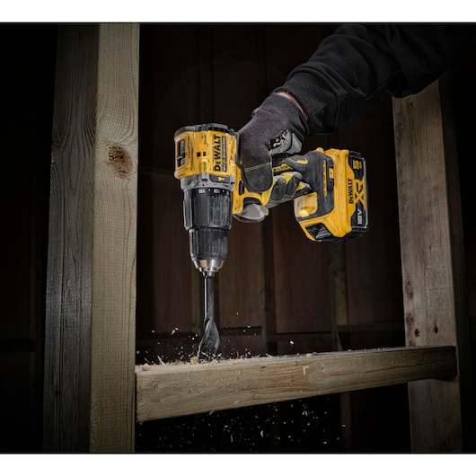 Worker in 100 years of DEWALT top drilling through timber stud wall