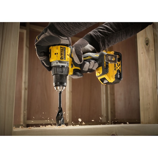 Close up of the 18V XR Brushless Compact Hammer Drill Driver with 18V 5Ah battery used by worker to drill wooden frame