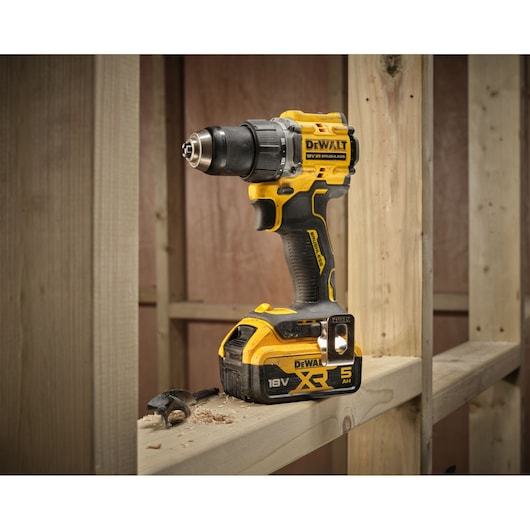 18V XR Brushless Compact Hammer Drill Driver with 18V 5Ah battery 3/4 view sitting on wooden frame