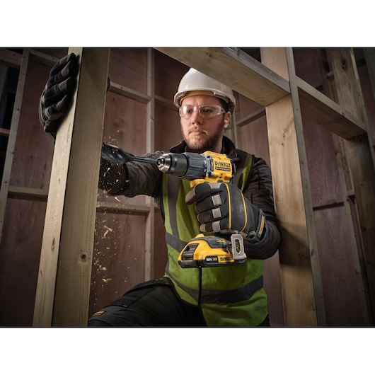 18V XR Brushless Compact Hammer Drill Driver with 18V 2Ah battery used by worker to drill wooden frame