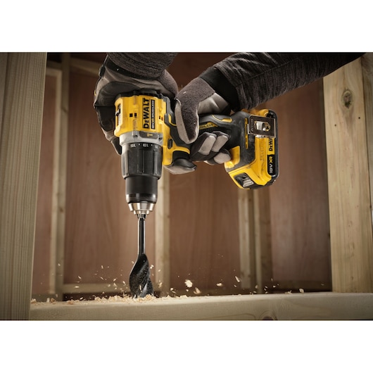 Close up of the 18V XR Brushless Compact Hammer Drill Driver with 18V 2Ah battery used by worker to drill wooden frame