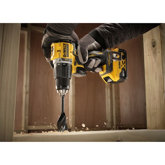 Close up of the 18V XR Brushless Compact Hammer Drill Driver with 18V 5Ah battery used by worker to drill wooden frame