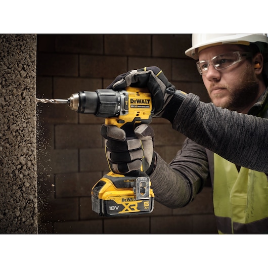 18V XR Brushless Compact Hammer Drill Driver with 18V 5Ah battery used by worker to drill concrete frame