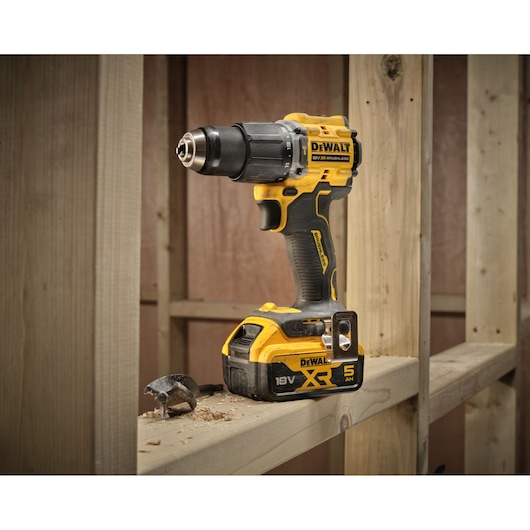 18V XR Brushless Compact Hammer Drill Driver with 18V 5Ah battery 3/4 view sitting on wooden frame