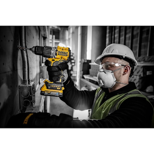 18V XR hammer drill driver with a compact Powerstack battery drilling a hole for a fastening