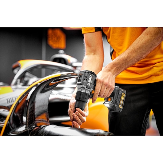 View of Limited Editon DEWALT/McLaren Drill Driver between fin of the car and the carbon fibre wheel  