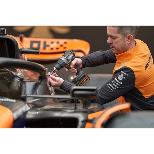 McLaren mechanic using DEWALT/McLaren drill driver on McLaren racing car