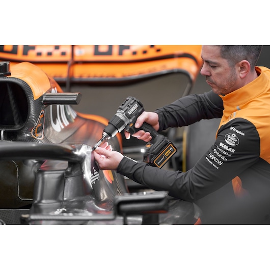 McLaren mechanic using DEWALT/McLaren drill driver on McLaren racing car