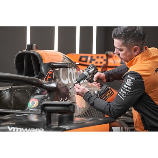McLaren mechanic using DEWALT/McLaren drill driver on McLaren racing car