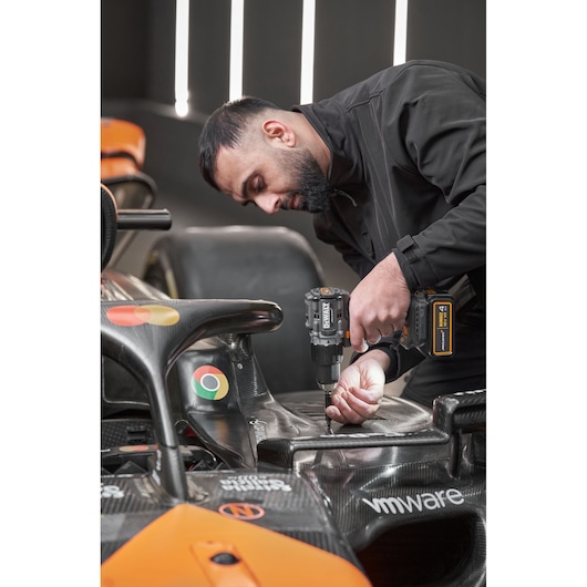McLaren mechanic using DEWALT/McLaren drill driver on McLaren racing car