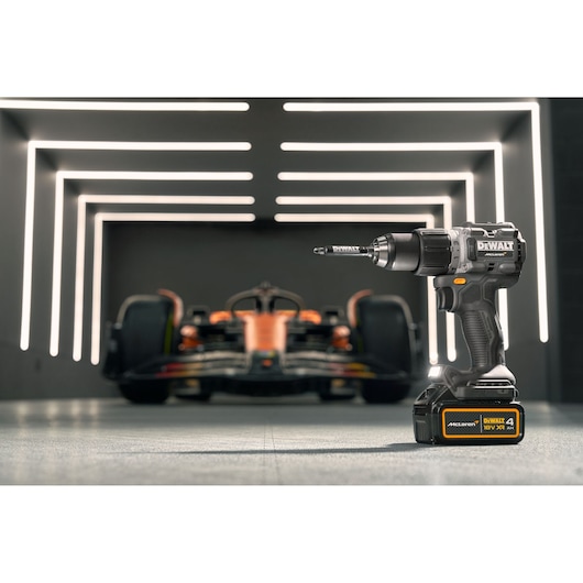 DEWALT/McLaren drill driver stands in the foreground with a McLaren racing car in the background