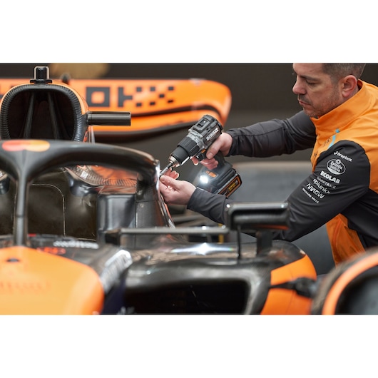 McLaren mechanic using DEWALT/McLaren drill driver on McLaren racing car