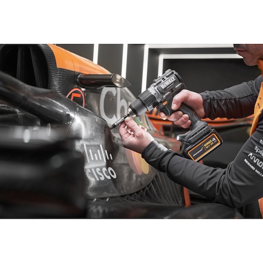 McLaren mechanic using DEWALT/McLaren drill driver on McLaren racing car