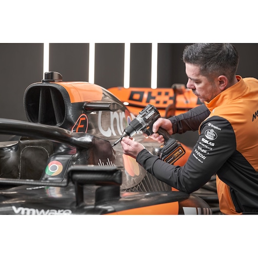 McLaren mechanic using DEWALT/McLaren drill driver on McLaren racing car