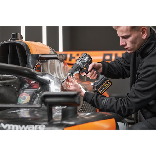 McLaren mechanic using DEWALT/McLaren drill driver on McLaren racing car