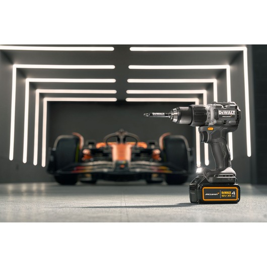DEWALT/McLaren drill driver stands in the foreground with a McLaren racing car in the background