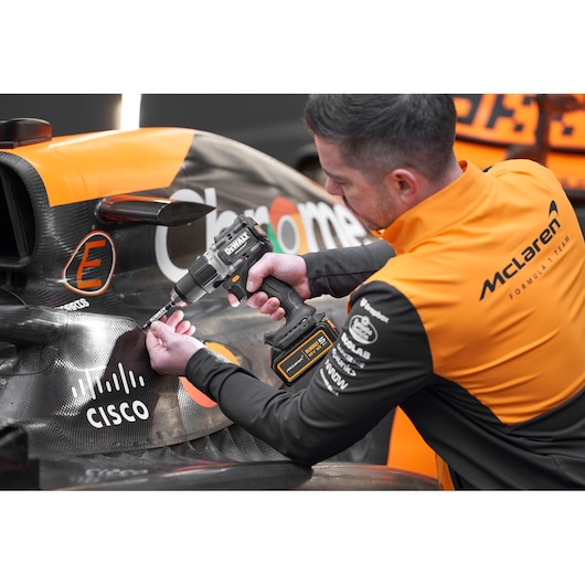McLaren mechanic using DEWALT/McLaren drill driver on McLaren racing car