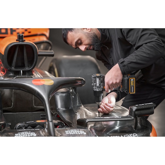 McLaren mechanic using DEWALT/McLaren drill driver on McLaren racing car