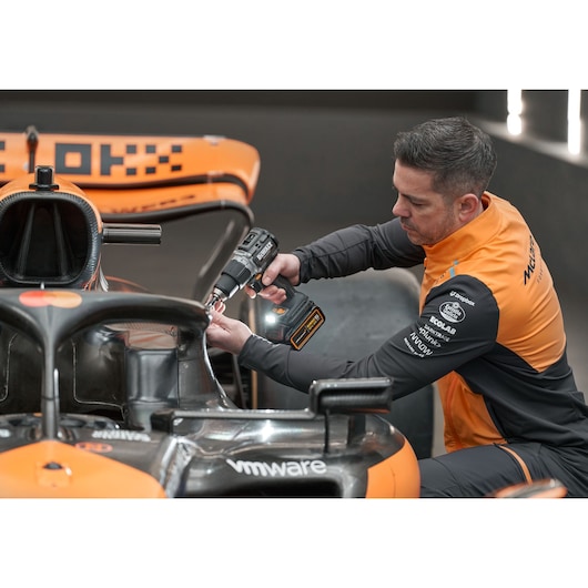 McLaren mechanic using DEWALT/McLaren drill driver on McLaren racing car
