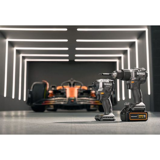 DEWALT/McLaren impact driver and drill driver stand in the foreground with a McLaren racing car in the background