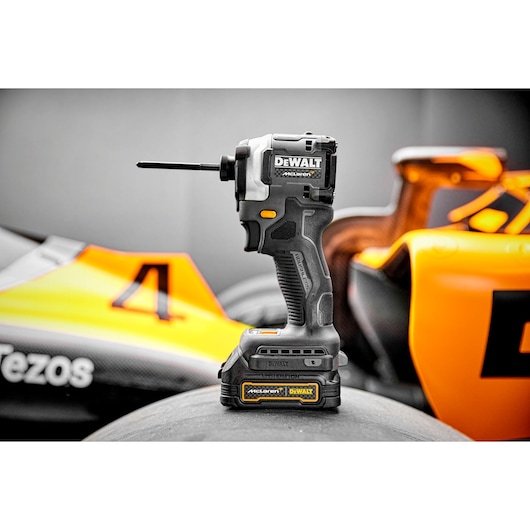 Landcsape shot of Limited Editon DEWALT/McLaren Impact Driver sitting on top of F1 car tyre