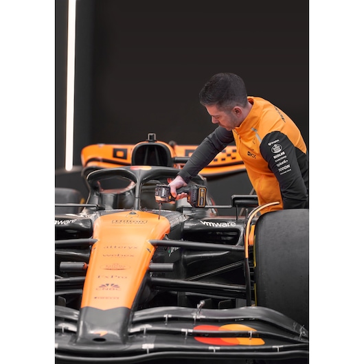 McLaren mechanic using DEWALT/McLaren impact driver on McLaren racing car