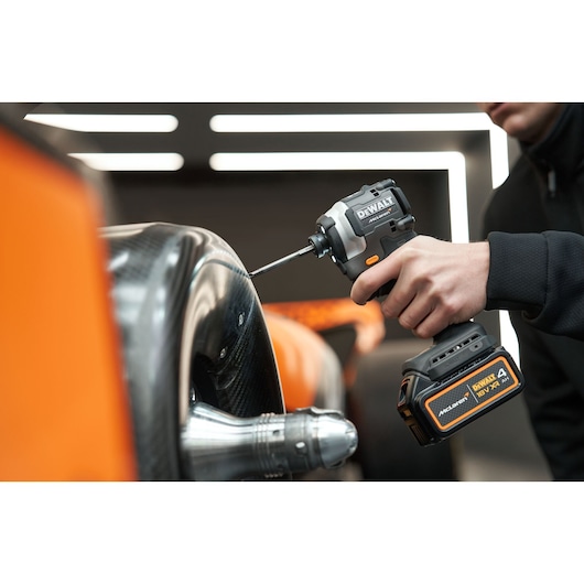 McLaren mechanic using DEWALT/McLaren impact driver on McLaren racing car