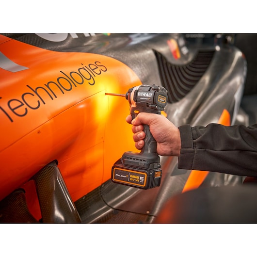 DEWALT/McLaren impact driver being used on side panel of racing car
