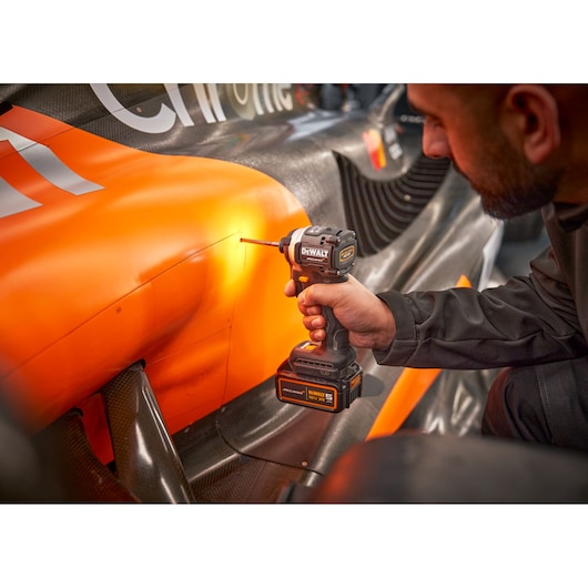 McLaren mechanic using DEWALT/McLaren impact driver on McLaren racing car