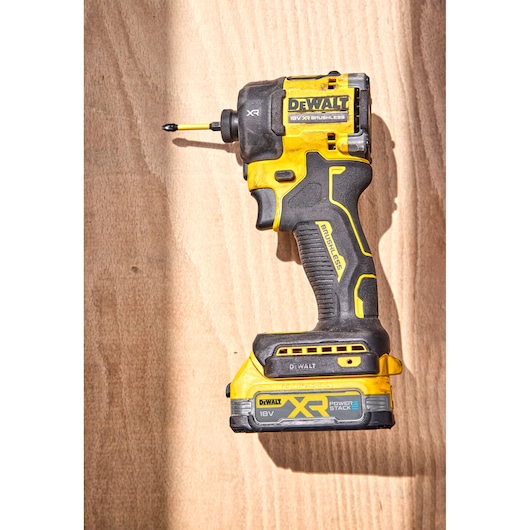 Overview of DCF870 18V XR Brushless impact driver laying on top of a wooden surface