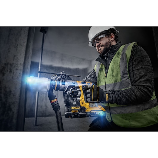 18V XR Brushless SDS-Plus Hammer Drill drilling into concrete wall using a dust extractor.