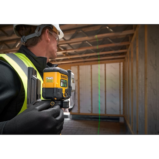 The DEWALT 3x 180 USB Green Beam Laser on tripod being set by worker on worksite.