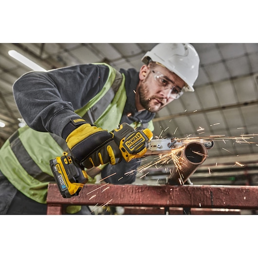 Worker in high vis using 18V XR Band File to sand metal pipe