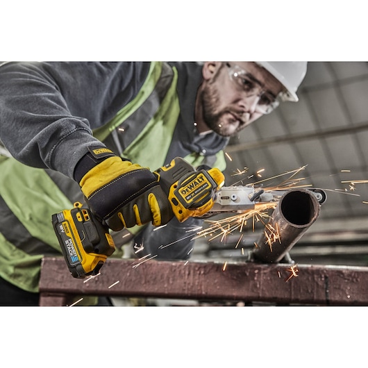 Worker using 18V XR Band File to sand metal pipe