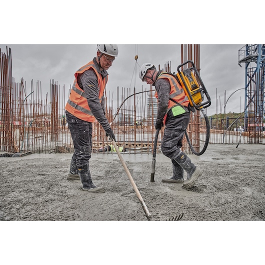 Construction workers raking concrete and pouring concrete using Powershift Backpack Concrete Vibrator