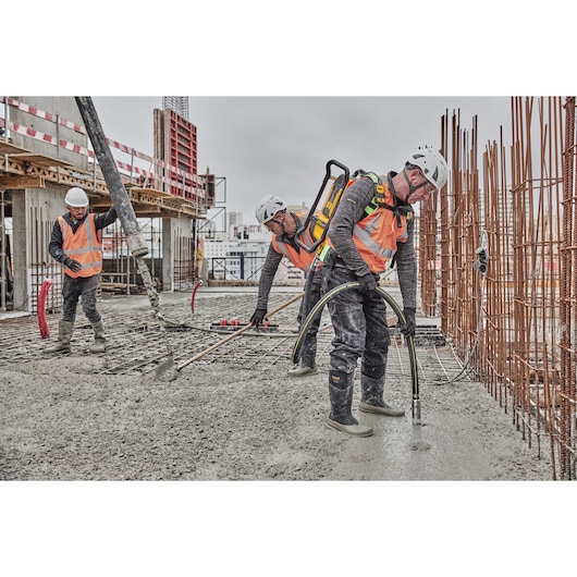 Concrete pouring on construction site. Worker closest to camera uses Powershift Backpack Concrete Vibrator