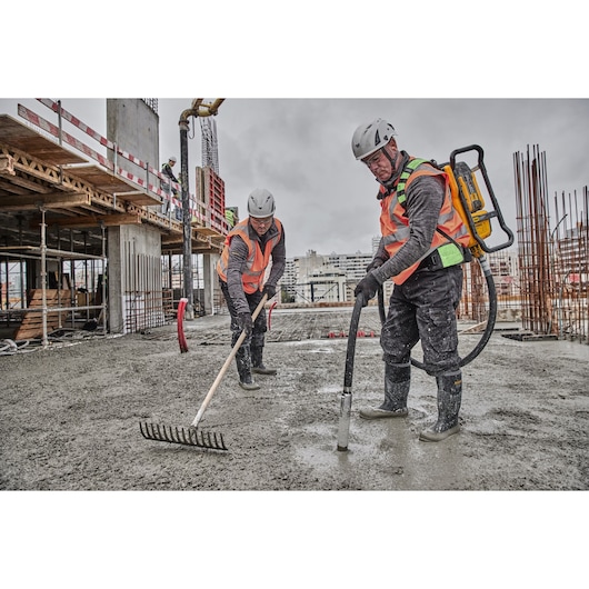 Concrete pouring and raking on construction site. Concrete is being poured using Powershift Backpack Concrete Vibrator