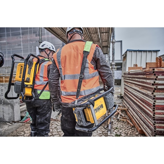 Two construction workers, each carrying a Powershift Backpack Concrete Vibrator