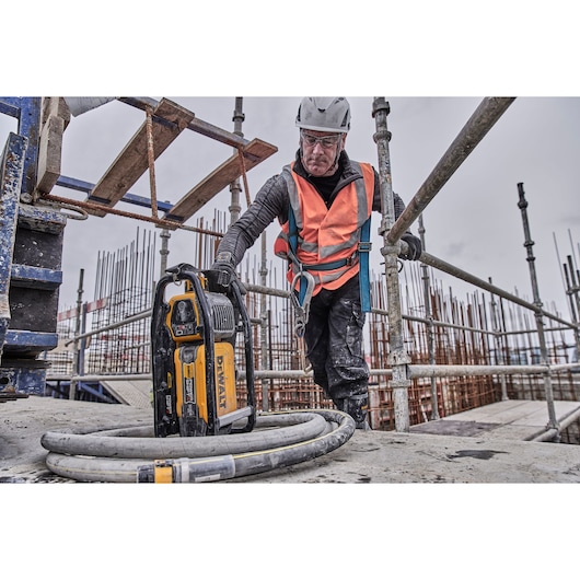 Construction worker reaching to pick up Powershift Powerpack Concrete Vibrator and hose
