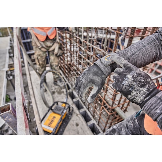 Construction worker use Wireless Tool Control attached to his wrist. Powershift Powerpack Concrete Vibrator is in the background